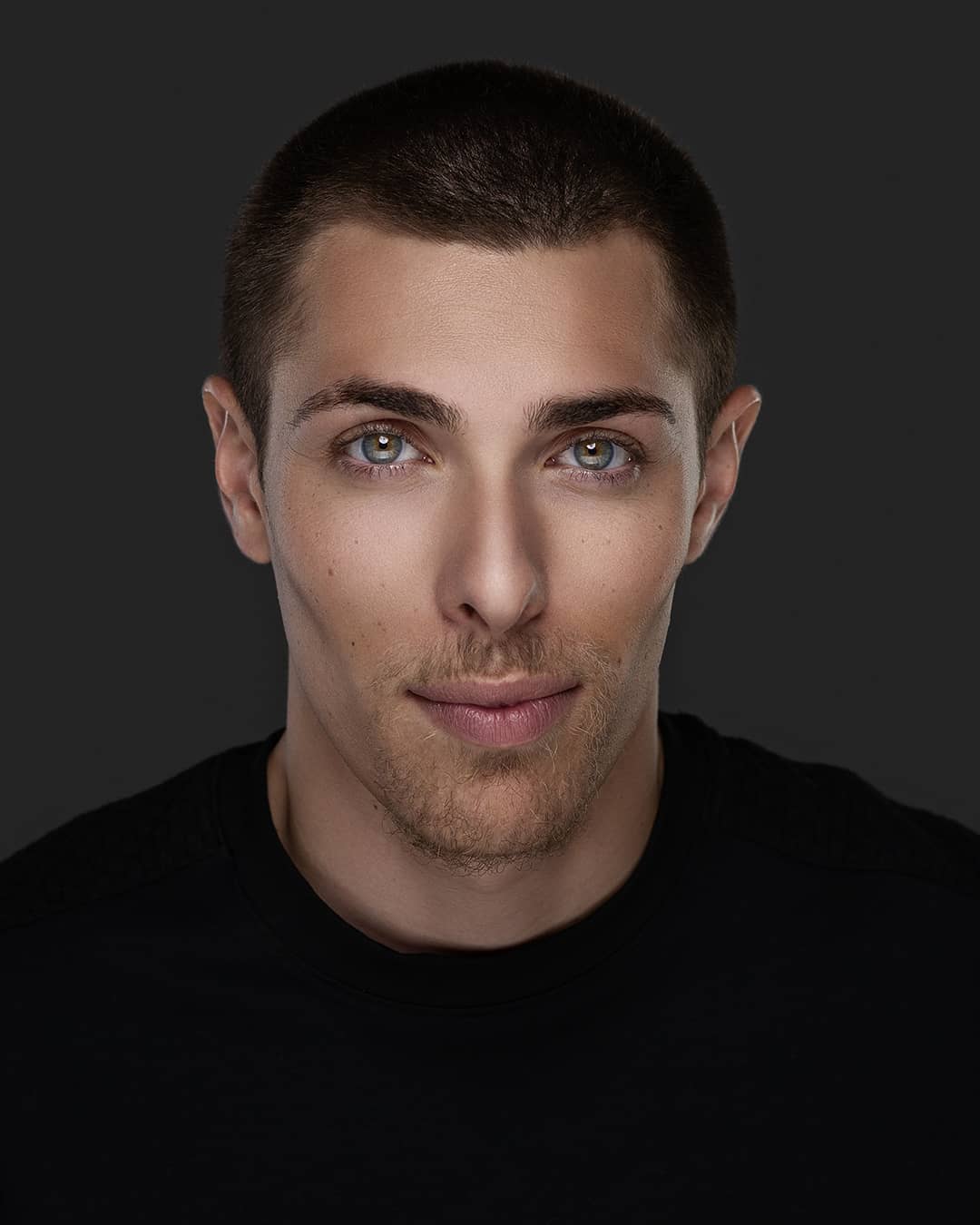Alex Veach (Alexander Veach) minimalist studio headshot, buzz cut, piercing blue-green eyes.