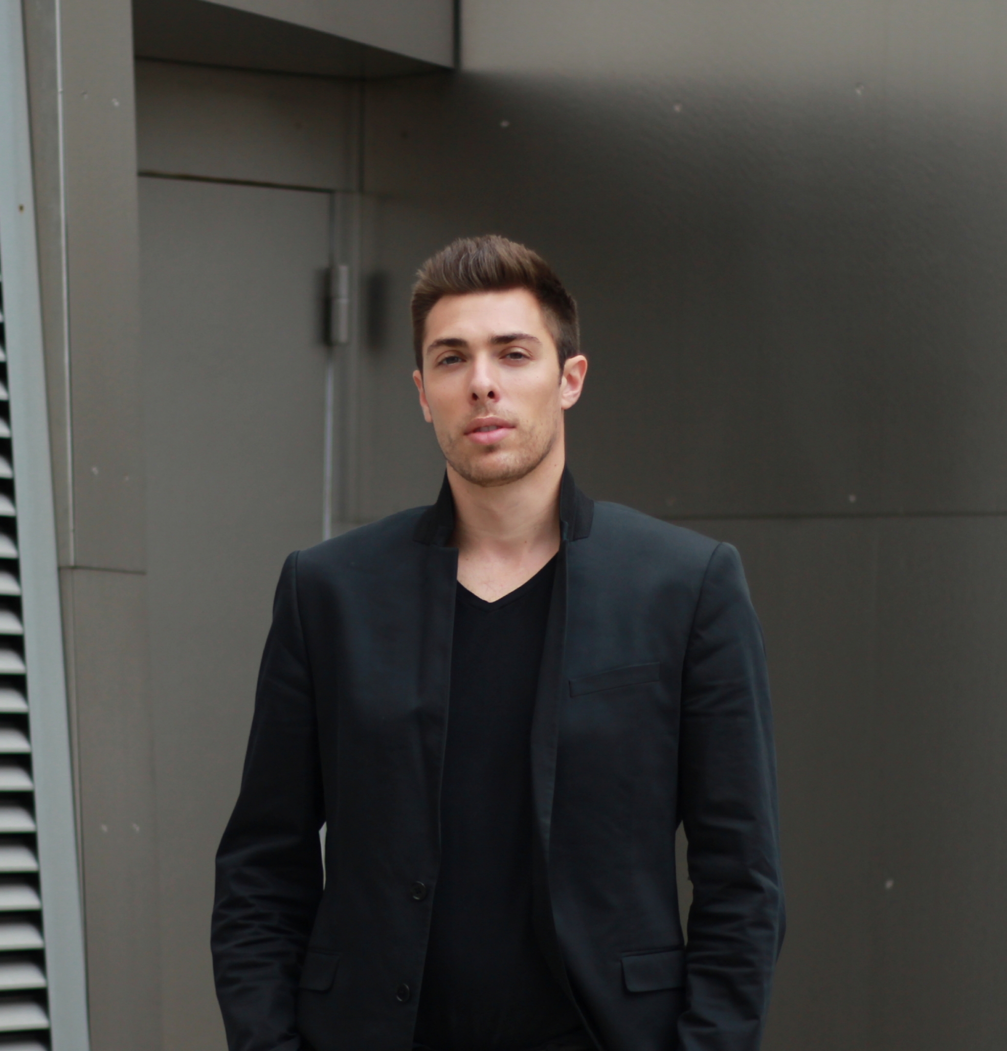 Alex Veach (Alexander Veach) LA street style, black blazer against metal panel wall.