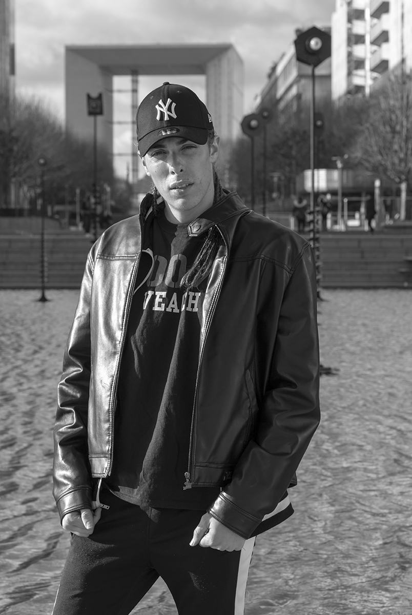 Alex Veach (Alexander Veach) Paris editorial, Yankees cap at the Grande Arche de la Defense.