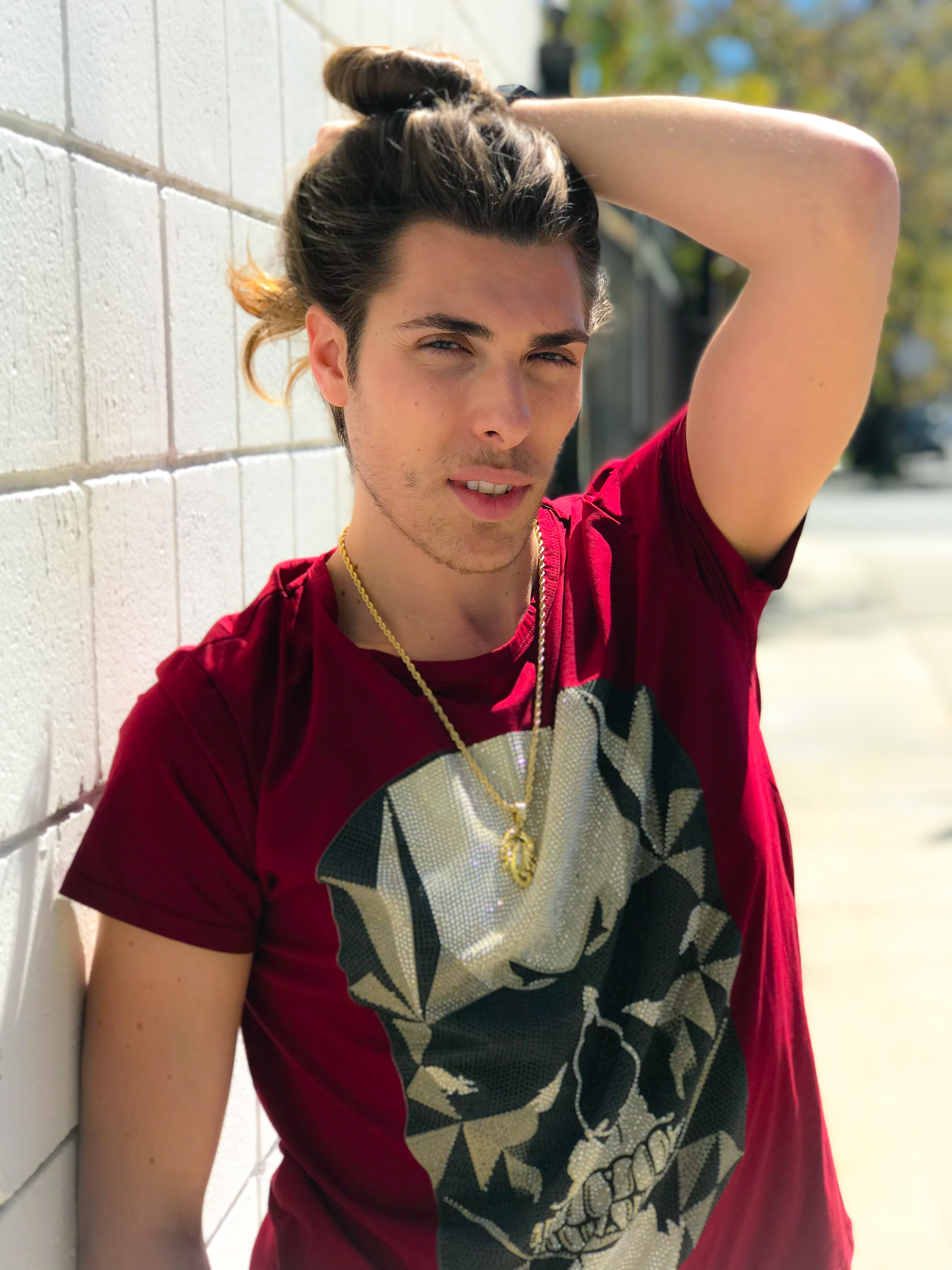 Alex Veach (Alexander Veach) LA streetwear, burgundy skull tee, confident smirk on white wall.